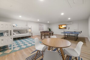 A room with bunk beds, a foosball table, a ping pong table, and a round table with chairs. - Hot Tub Sportscourt Game Room 5 min to Beach (Seminole)