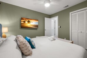 A bedroom with a bed, pillows, a nightstand, a painting, a door, and a closet. - Hot Tub Sportscourt Game Room 5 min to Beach (Seminole)