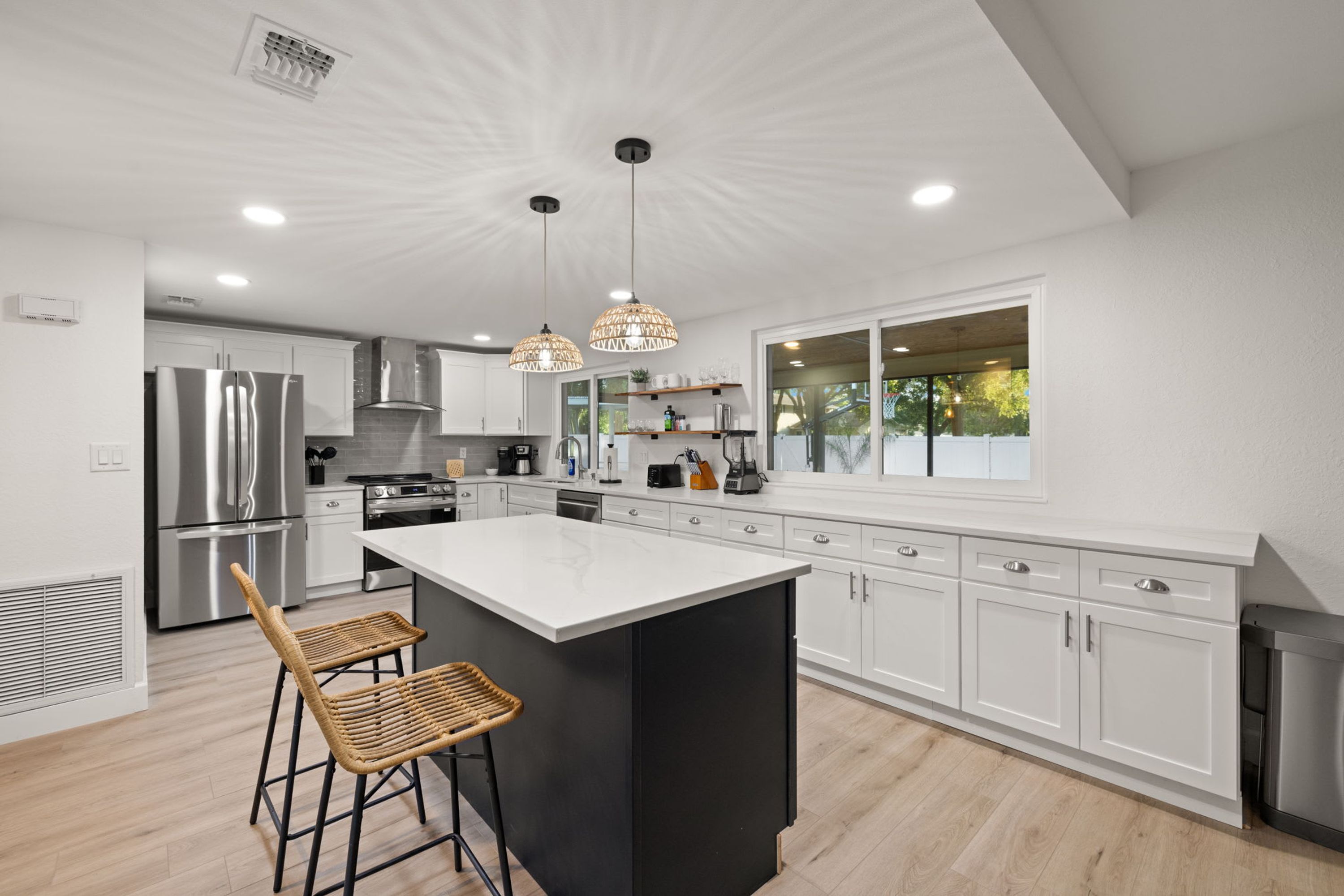 Una cocina moderna con muebles blancos, una isla grande y un taburete de bar.