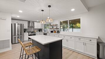 Una cocina moderna con muebles blancos, una isla grande y un taburete de bar.
