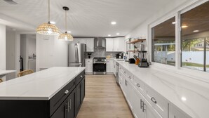 A modern kitchen with a large island, stainless steel appliances, and pendant lighting. - Hot Tub Sportscourt Game Room 5 min to Beach (Seminole)