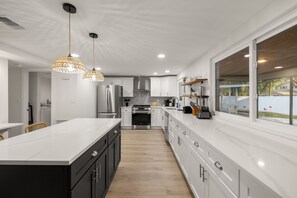 A modern kitchen with a large island, stainless steel appliances, and pendant lighting. - Hot Tub Sportscourt Game Room 5 min to Beach (Seminole)