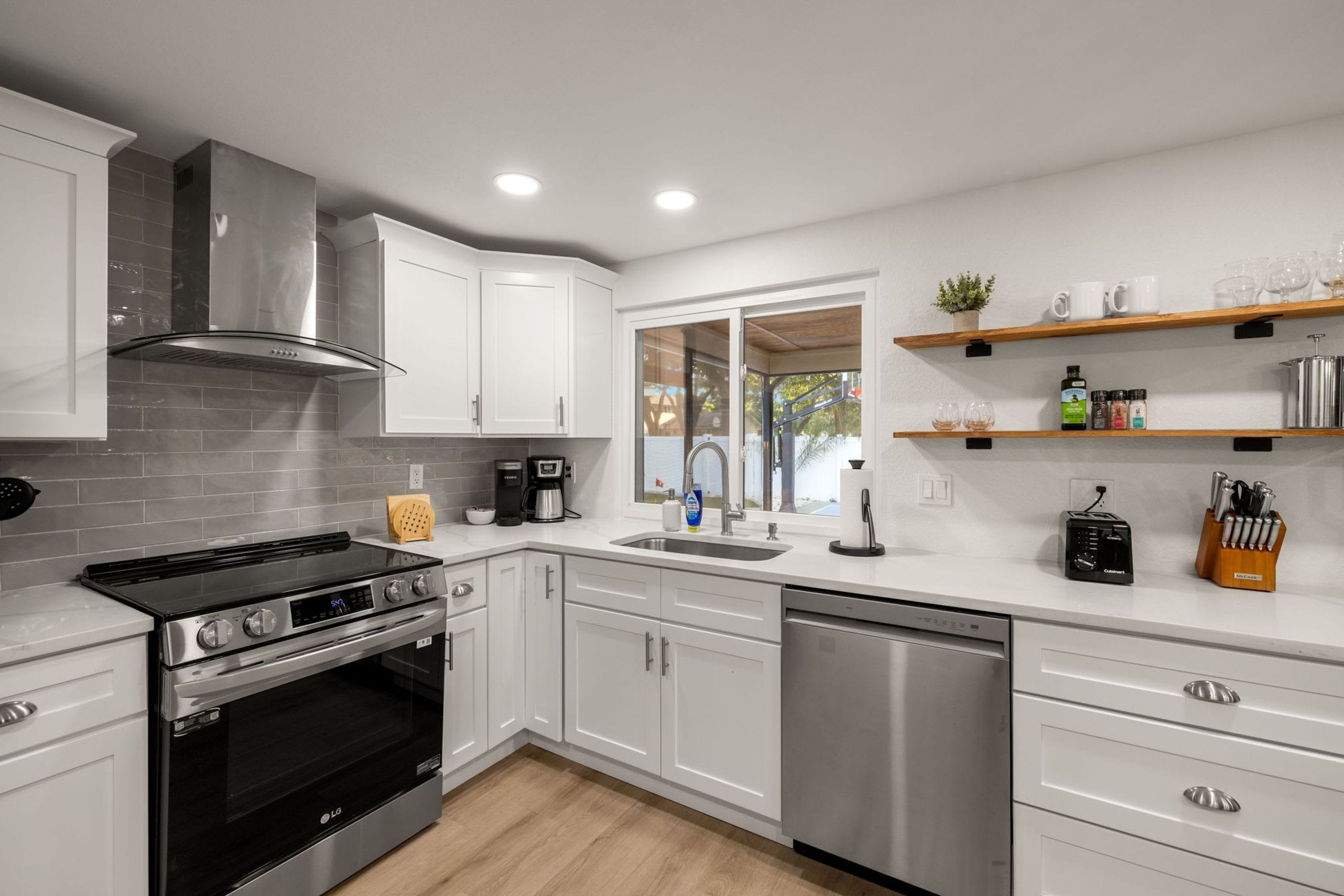 Una cocina moderna con gabinetes blancos, electrodomésticos de acero inoxidable y un ventanal con vistas al exterior.