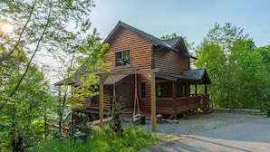 A wooden cabin with a porch, surrounded by trees and a gravel driveway. - Ski In Out Hatley Pointe Views Hottub Fire Pit (Mars Hill)