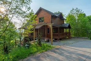 A wooden cabin with a porch, surrounded by trees and a gravel driveway. - Ski In Out Hatley Pointe Views Hottub Fire Pit (Mars Hill)