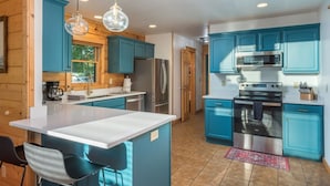 A modern kitchen with blue cabinets, stainless steel appliances, and a central island. - Ski In Out Hatley Pointe Views Hottub Fire Pit (Mars Hill)