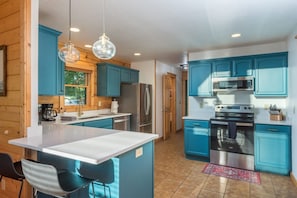 A modern kitchen with blue cabinets, stainless steel appliances, and a central island. - Ski In Out Hatley Pointe Views Hottub Fire Pit (Mars Hill)