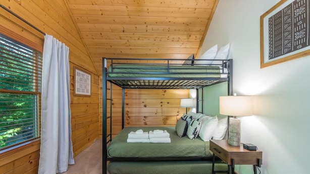 A bunk bed room with a green mattress, a bedside table with a lamp, and a window with blinds. - Ski In Out Hatley Pointe Views Hottub Fire Pit (Mars Hill)