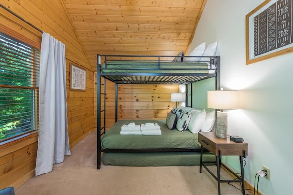 A bunk bed room with a green mattress, a bedside table with a lamp, and a window with blinds. - Ski In Out Hatley Pointe Views Hottub Fire Pit (Mars Hill)