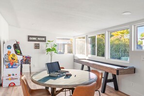 A room with a glass table, chairs, a desk, and a gaming machine. - The Desert Emerald Pool Hot Tub Games More (Scottsdale)