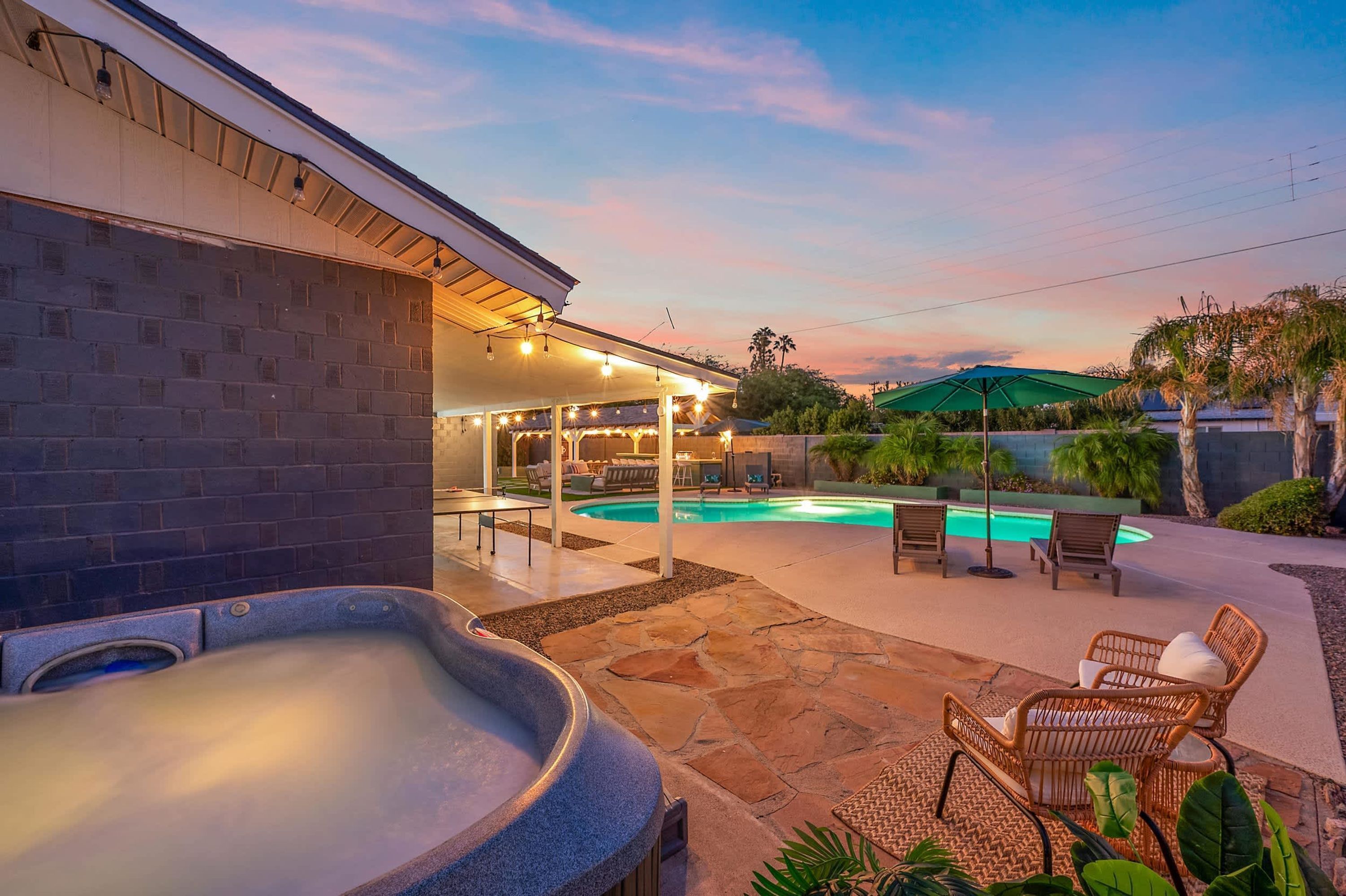 Un jardin avec un jacuzzi, une piscine, du mobilier d’extérieur et un patio couvert.