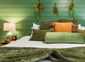 A bed with green bedding, a bedside lamp, and a small plant on a nightstand. - The Desert Emerald Pool Hot Tub Games More (Scottsdale)