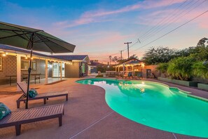 A swimming pool with a curved edge, surrounded by a patio area with lounge chairs and a covered seating area. - The Desert Emerald Pool Hot Tub Games More (Scottsdale)