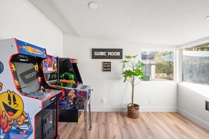 A room with arcade games, a 'GAME ROOM' sign, a plant, and a window with a view. - The Desert Emerald Pool Hot Tub Games More (Scottsdale)