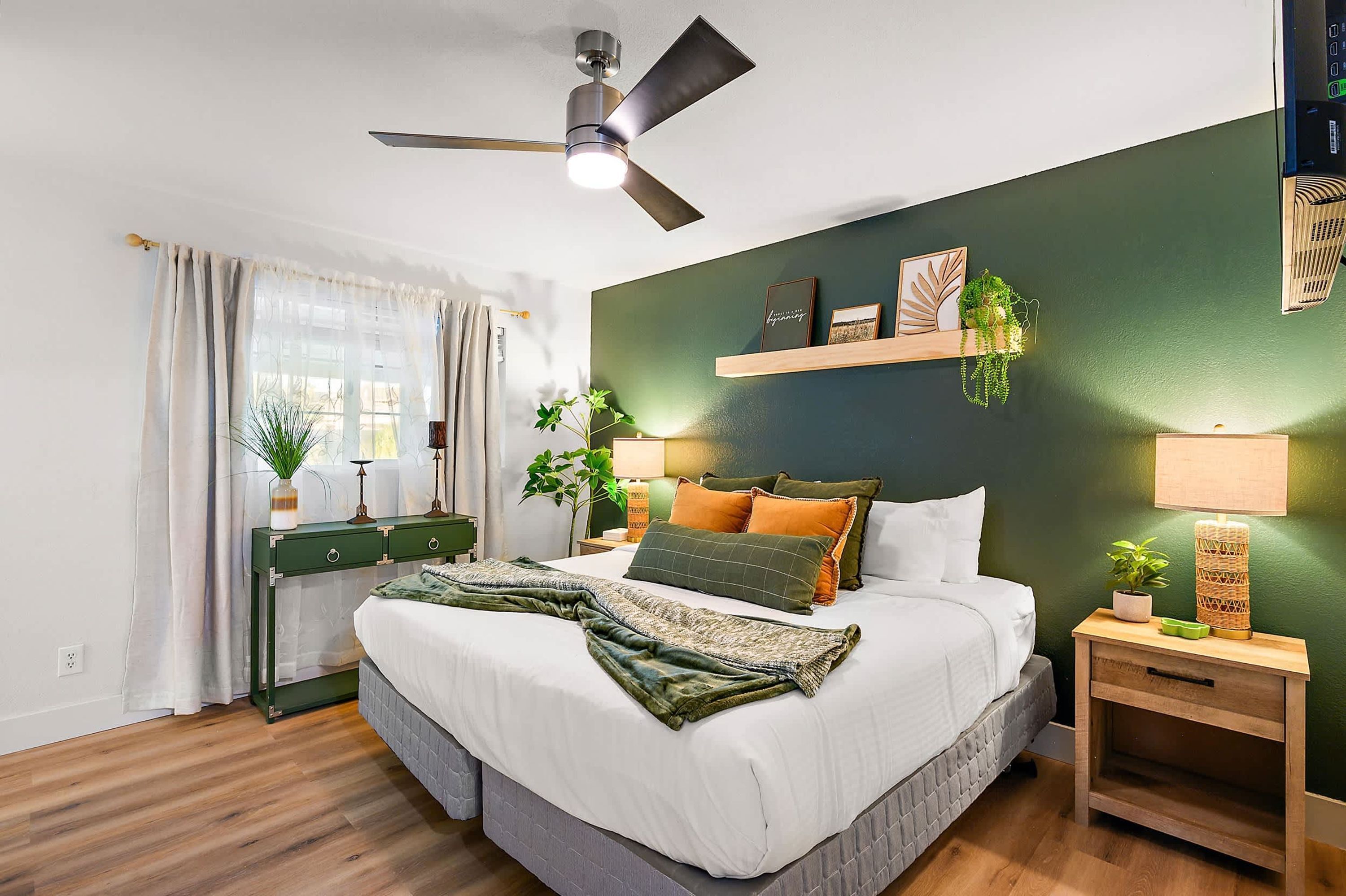 A bedroom with a bed, bedside tables, a ceiling fan, and a window with curtains.