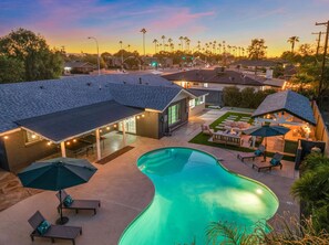 A residential area with a swimming pool, outdoor seating, and a covered patio area. - The Desert Emerald Pool Hot Tub Games More (Scottsdale)
