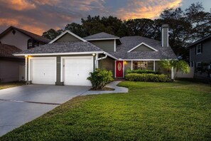 Una casa residenziale con due garage annessi, una porta rossa e un prato curato.
