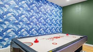 A room with a pool table, green walls, and a blue leaf-patterned wallpaper.