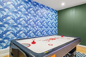 Una habitación con mesa de billar, paredes verdes y papel tapiz con diseño de hojas azules.