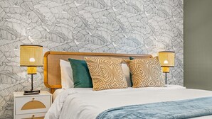 Une chambre à coucher avec un lit, deux lampes de chevet, une table de chevet et un papier peint à motifs.