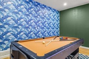 A pool table with a blue leaf pattern wallpaper and a green wall. - Tiki Bar Pool Putt Putt 1 Mile From Beach (Seminole)