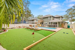 A backyard with a swimming pool, a grassy area, and a wooden deck. - Tiki Bar Pool Putt Putt 1 Mile From Beach (Seminole)