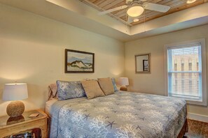 Ein Schlafzimmer mit Bett, Deckenventilator, Fenster mit Jalousien und einem Bild an der Wand.
