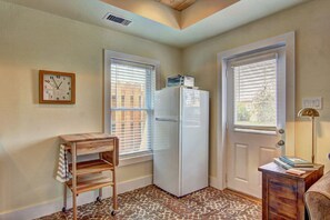 Una cocina pequeña con un refrigerador, una mesa de madera y un reloj en la pared.