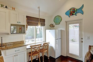 Uma cozinha com geladeira, mesa de jantar com cadeiras, luminária pendente e decoração na parede.