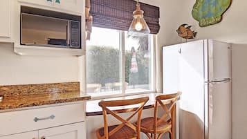 Cocina compacta con refrigerador, microondas y sillas de madera.