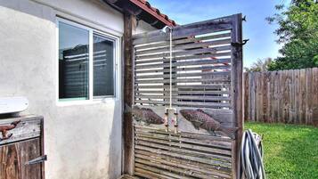 Um portão de madeira com uma tranca de metal, uma janela e um deck de madeira.