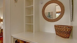 Ein heller Innenraum mit einem Korbregal, einem runden Spiegel und einem Kamin mit Holzscheit.