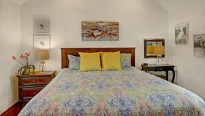 Ein Schlafzimmer mit einem großen Bett, einem Nachttisch, einer Wandlampe und einem Beistelltisch.