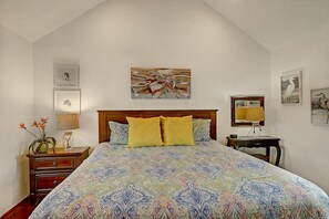 A bedroom with a large bed, a nightstand, a bedside table, and a wall-mounted lamp. - Cozy Private Cottage Pet Friendly Prime Location (Port Aransas)
