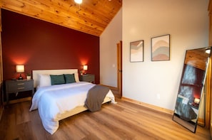 A bedroom with a wooden ceiling, a bed with white bedding, two bedside lamps, and two wall-mounted pictures. - The Triple Timber in Mars Hill (Mars Hill)