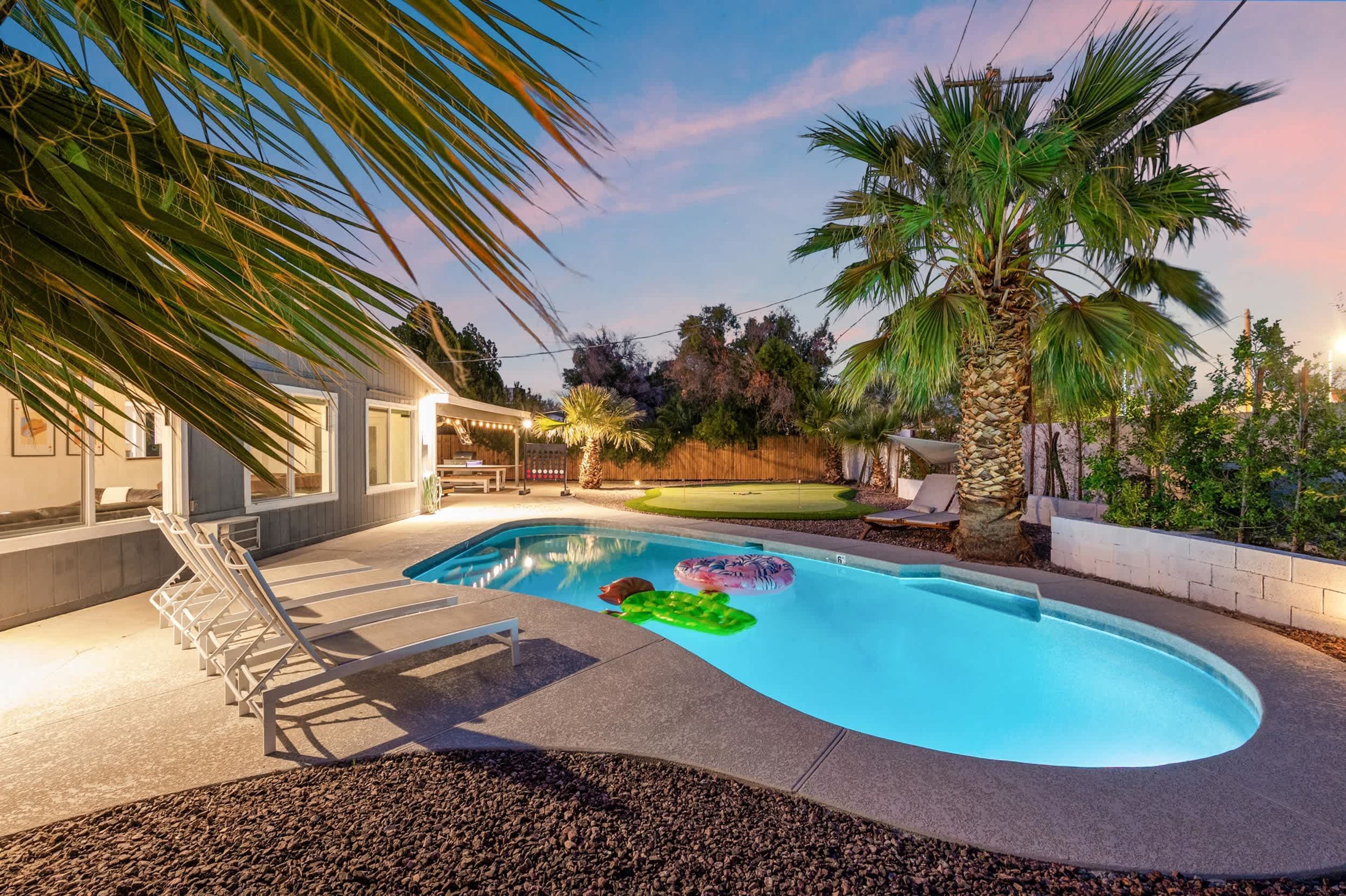 A swimming pool with lounge chairs and palm trees.