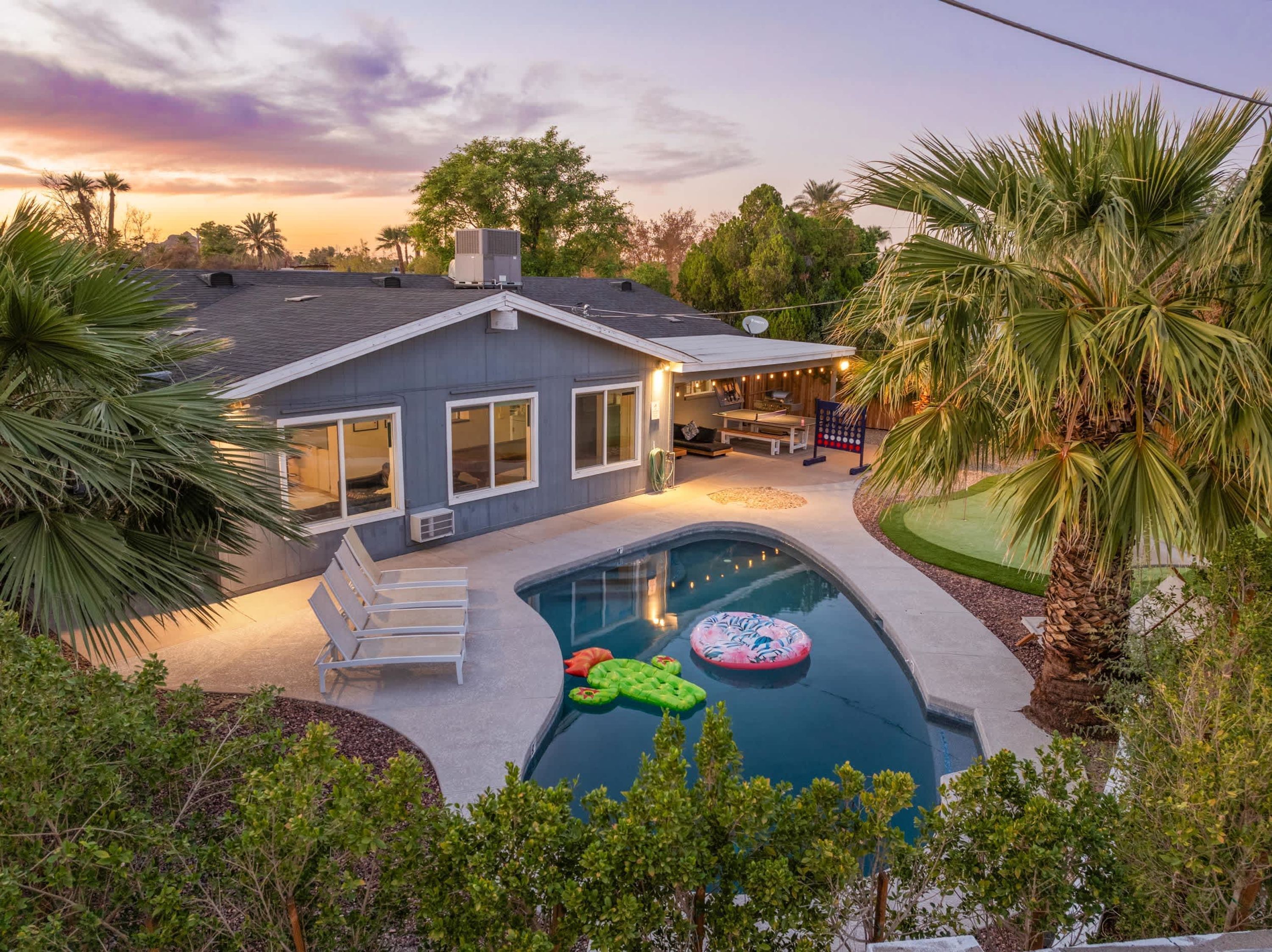 A residential property with a swimming pool, outdoor seating area, and a covered patio.