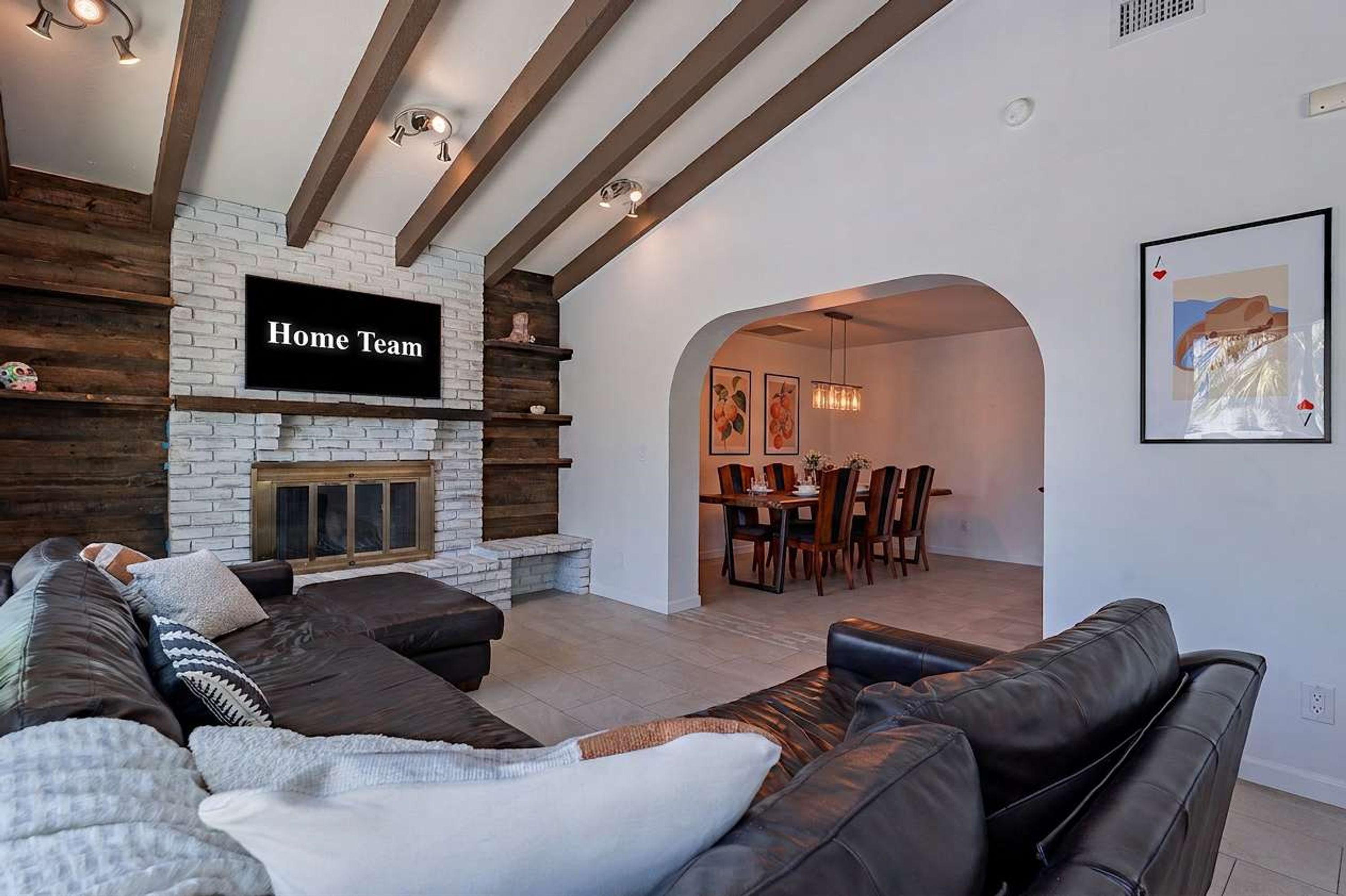 Una sala de estar moderna con chimenea de piedra, un sofá y un comedor con sillas y una mesa.