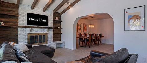 A modern living room with a stone fireplace, a sofa, and a dining area with chairs and a table.