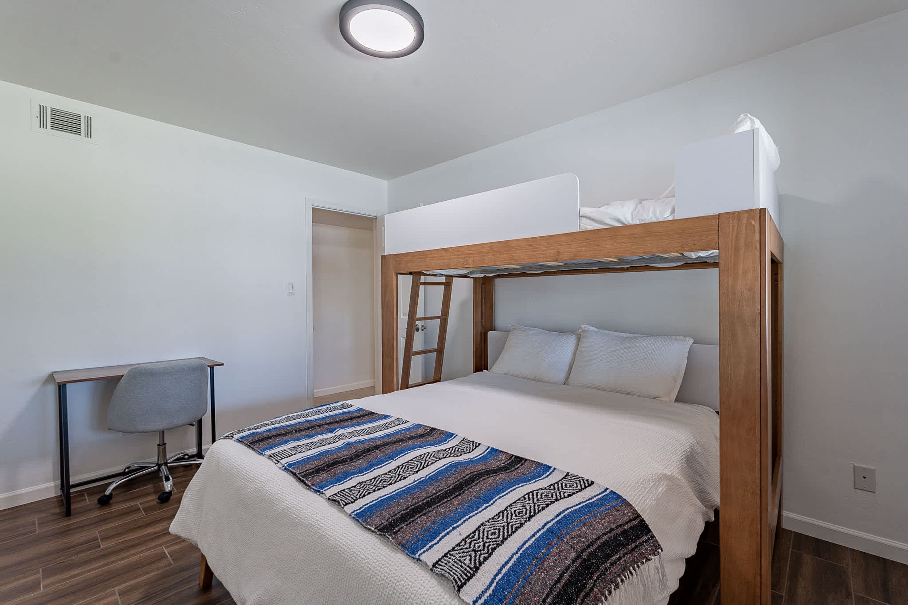 A single-bed room with a bunk bed, a desk, and a chair.