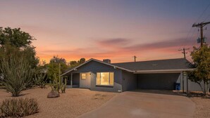 Une maison de plain-pied avec un garage, une allée et un paysage désertique parsemé de cactus.
