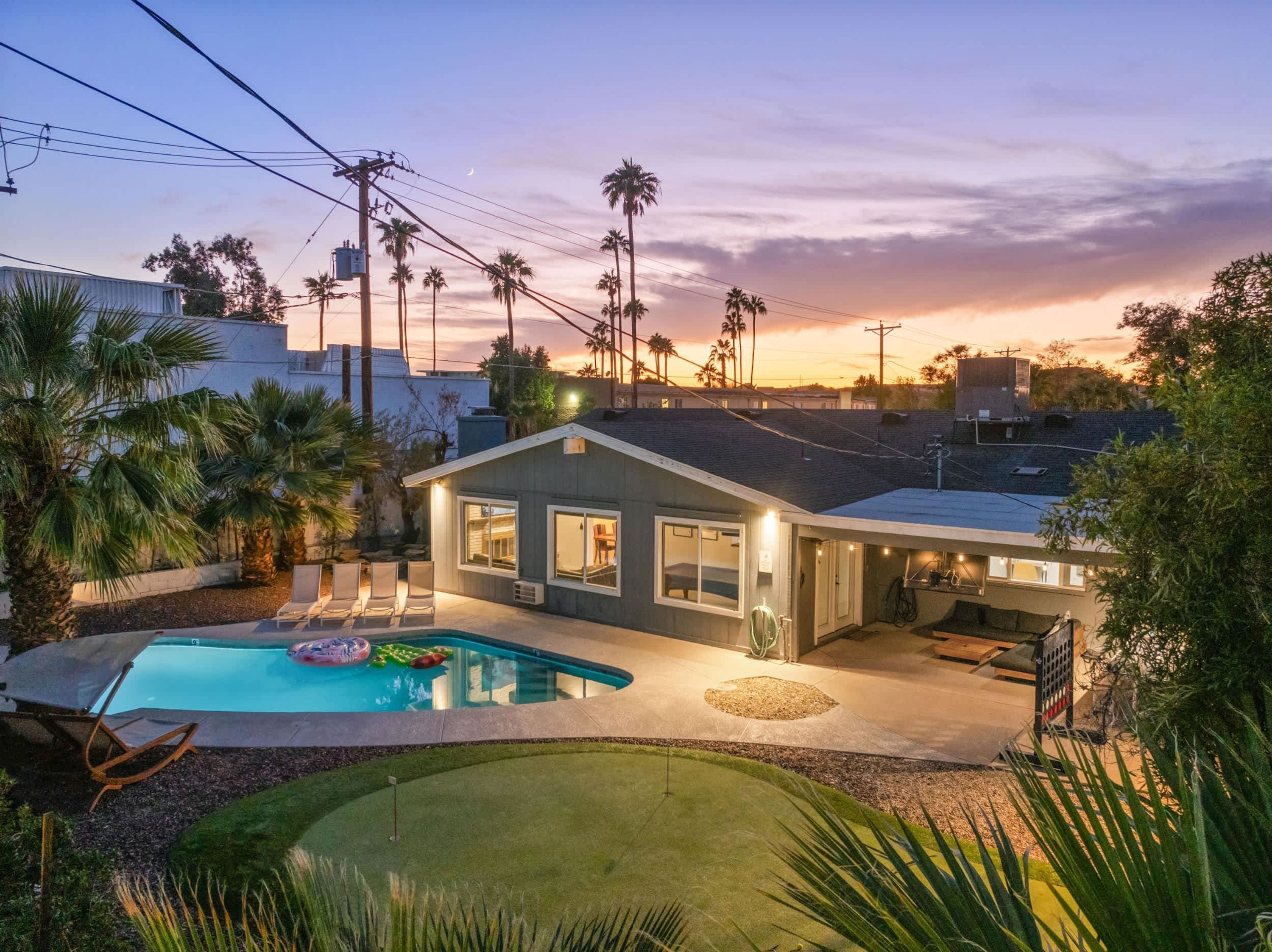 Ein Wohnhaus mit Pool, überdachter Terrasse und Blick auf den Sonnenuntergang.