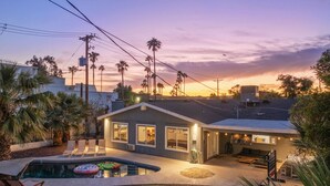 Une maison moderne dotée d’une piscine, d’un patio et offrant une vue sur le coucher de soleil.