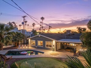Ein modernes Haus mit Pool, Terrasse und Blick auf den Sonnenuntergang.