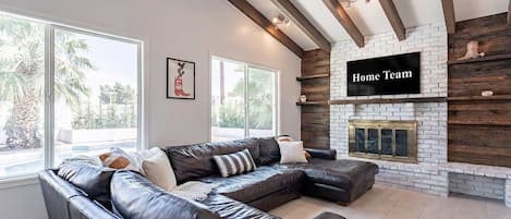 A living room with a sectional sofa, a fireplace, and a sign that reads 'Home Team'.