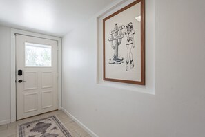 A hallway with a white door, a framed welcome sign, and a patterned rug. - 4 Br Tempe Retreat Pool Putt Putt Pool Table (Tempe)
