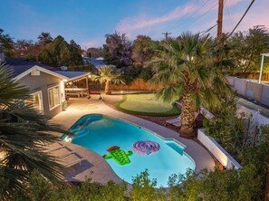 A swimming pool with inflatable toys, a patio area, and a lawn. - 4 Br Tempe Retreat Pool Putt Putt Pool Table (Tempe)