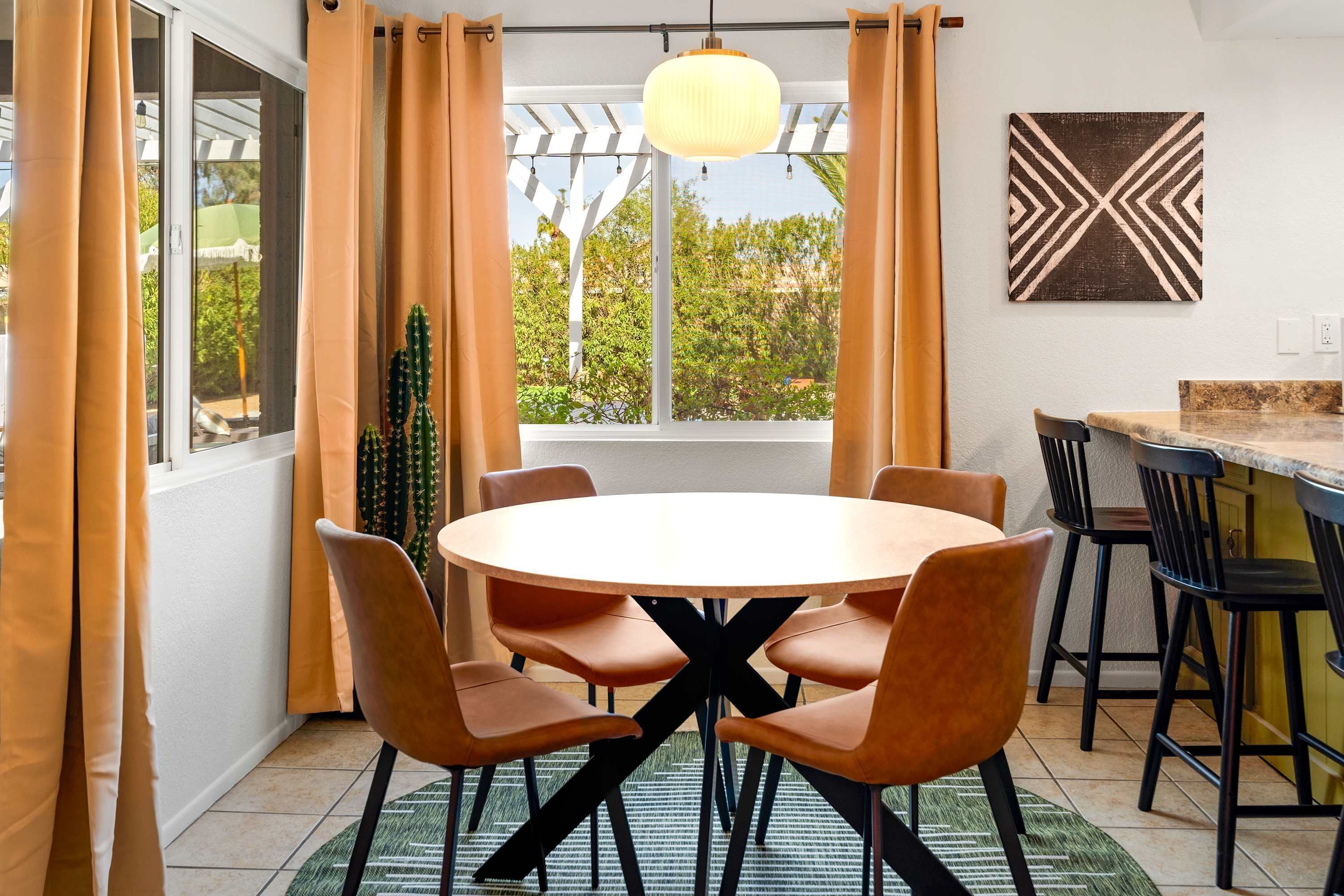 A dining area with a round table, six chairs, and a hanging light fixture.