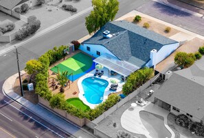 Ein Wohnhaus mit Schwimmbad, Tennisplatz und überdachter Terrasse.