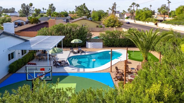 A residential area with a swimming pool, patio furniture, and a basketball court. - Epic Desert Stay Pool Hot Tub Sports Court (Scottsdale)